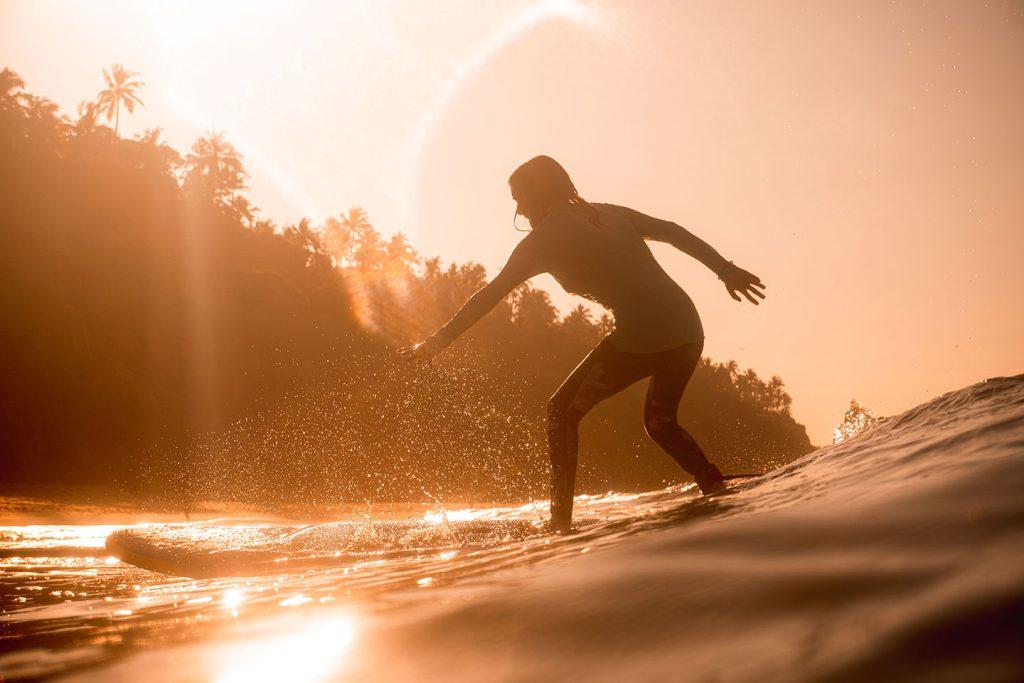 Surf instructor guiding beginner on a wave at Varkala beach, Kerala