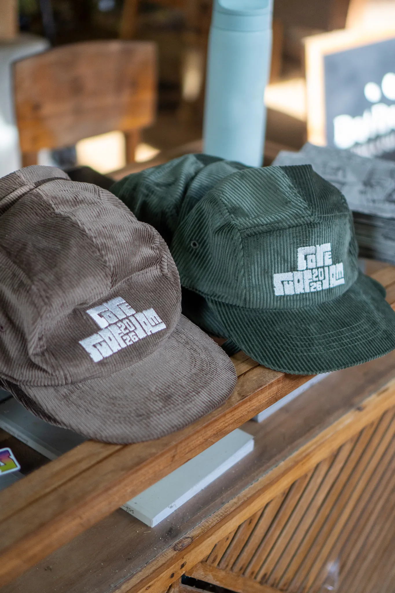 Corduroy caps embroidered with the Cove Surf Jam 2026 logo on the shop counter