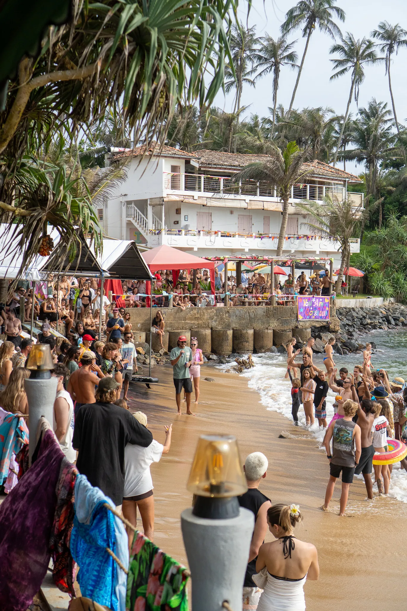Crowd gathered on the beach at Cove Surf Jam, cheering surfers in the water