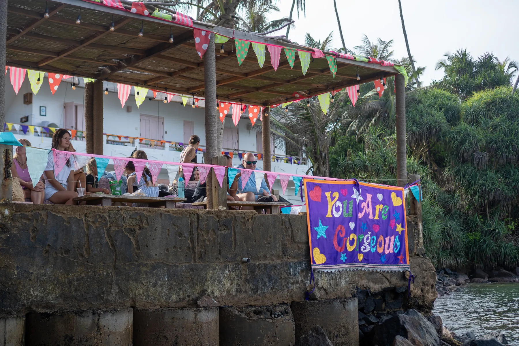 Hand-painted “You Are Gorgeous” banner and bunting strung along the deck above the cove