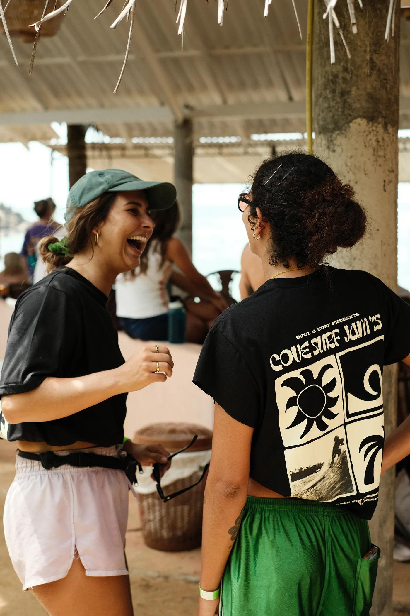 Two guests laughing, one wearing the black Cove Surf Jam 2026 T-shirt